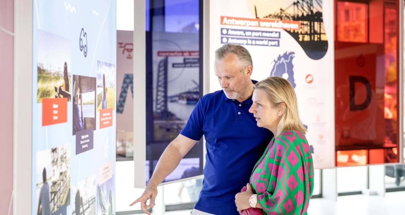 Een man en vrouw die naar een informatiebord kijken in het belevingscentrum Havenwerld.