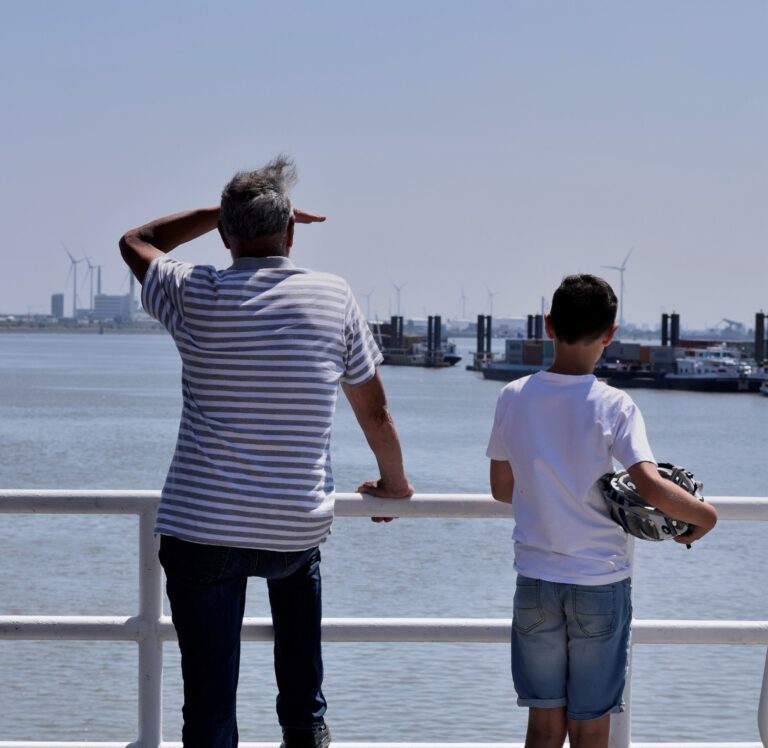 Man en jongen die over de haven uitkijken
